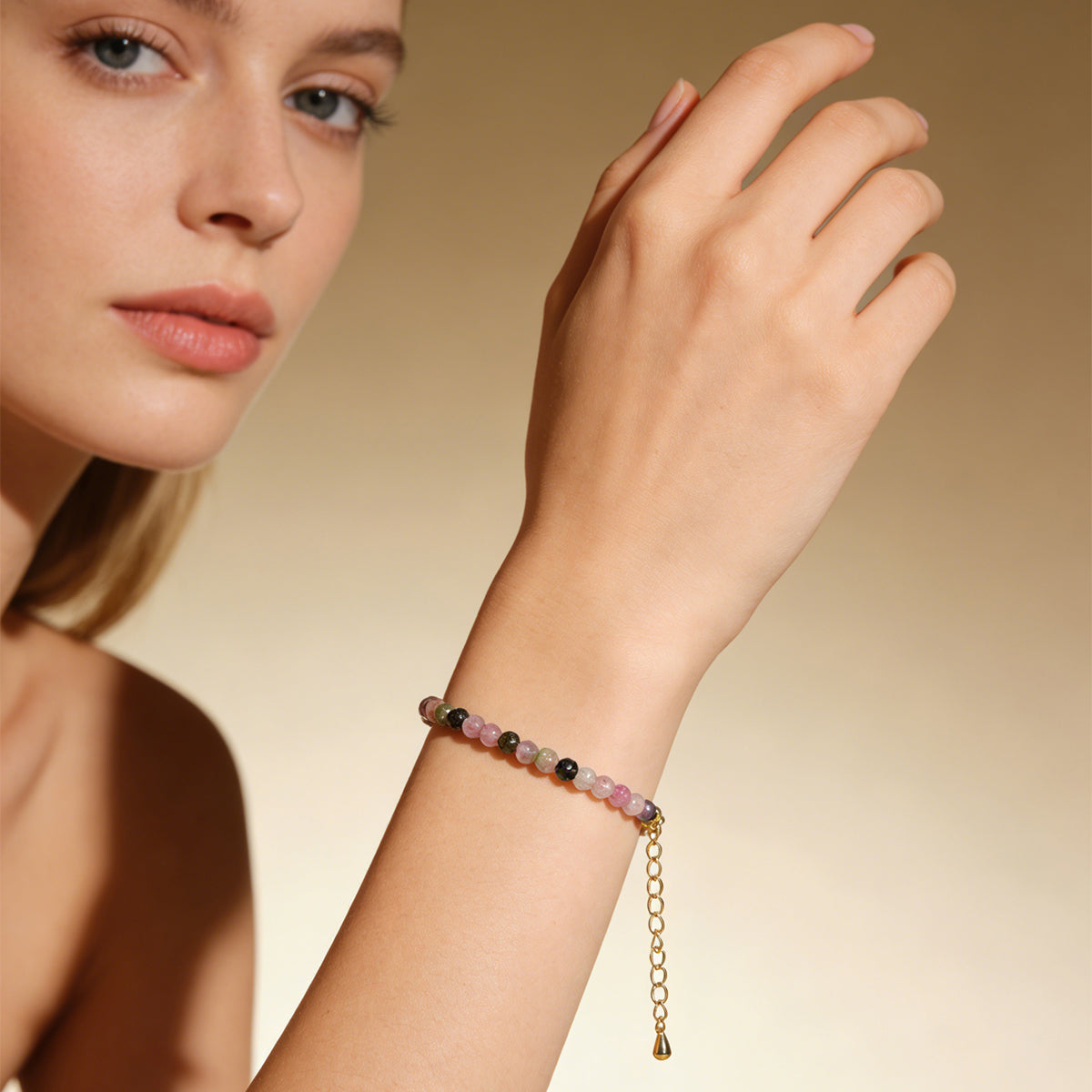 Tourmaline beaded bracelet on wrist with gold chain tassel