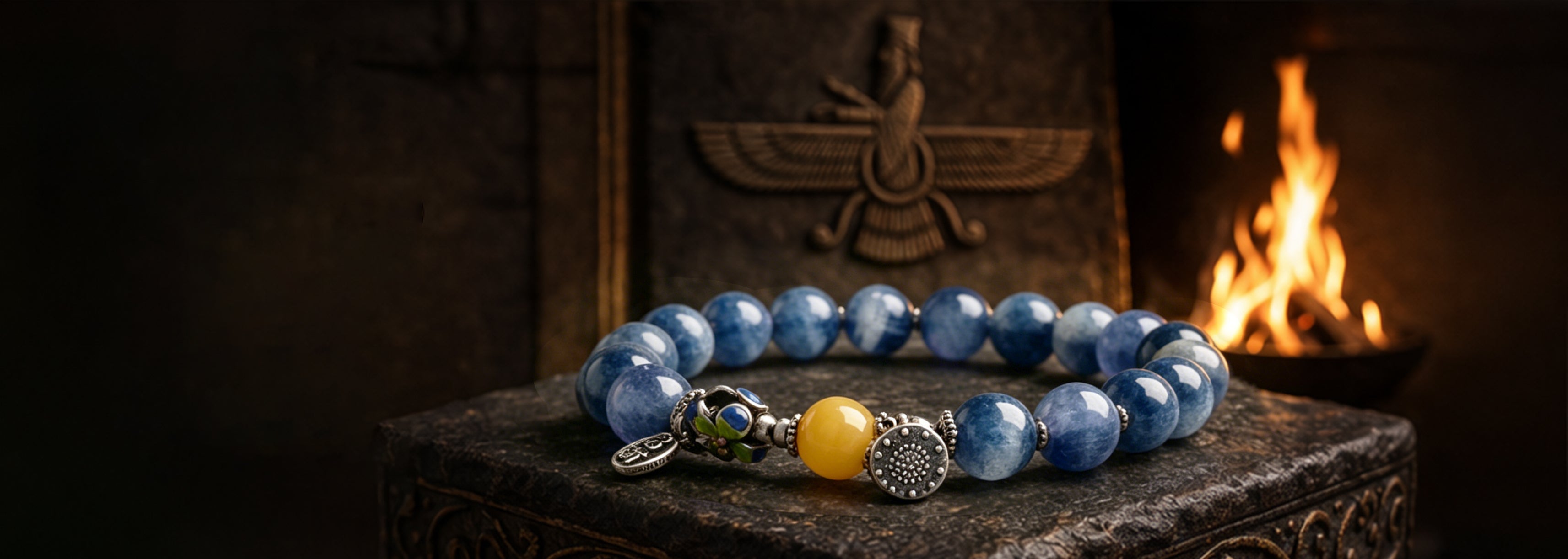 Blue Kyanite crystal bracelet with a yellow agate bead, displayed in front of a Zoroastrian Faravahar symbol and sacred fire.