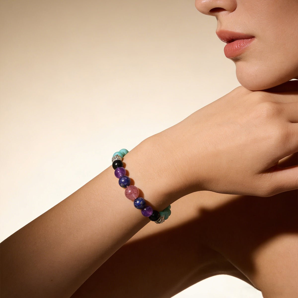 Beaded crystal bracelet on wrist with teal, purple, black, and pink beads plus silver spacers