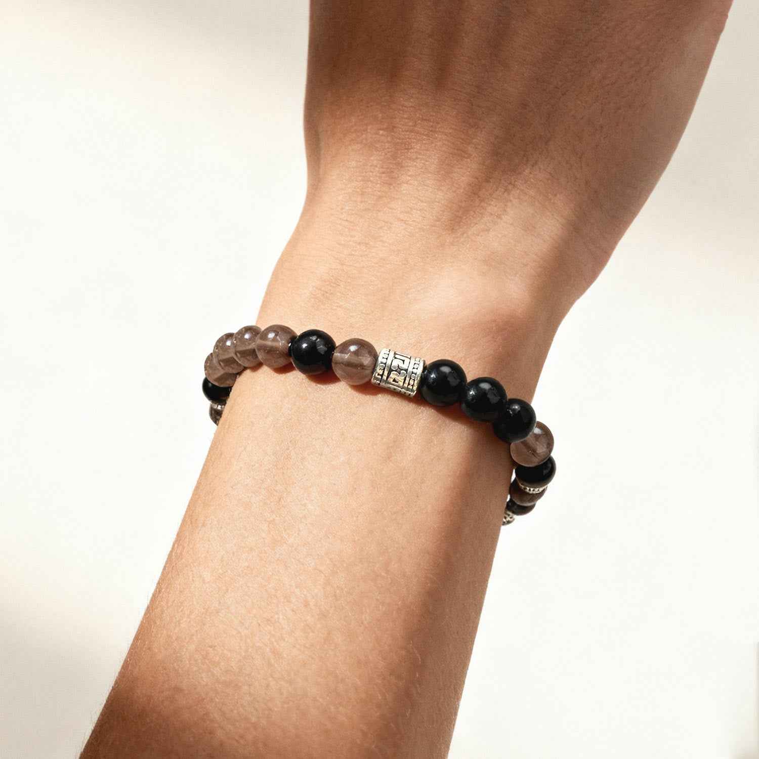 Crystal beaded bracelet on wrist with black and smoky brown beads and silver spacer details.
