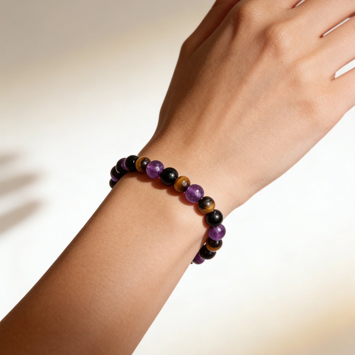 Crystal bead bracelet on wrist close-up with black, purple, and brown beads