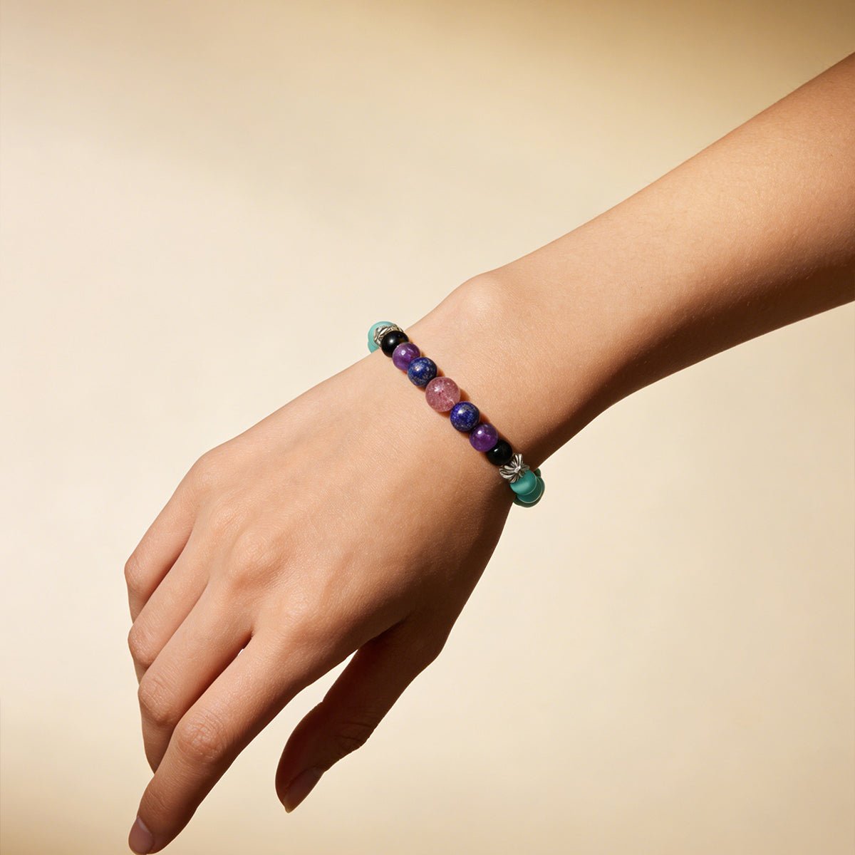 Beaded crystal bracelet on hand with teal, purple, black, and pink beads and silver spacers