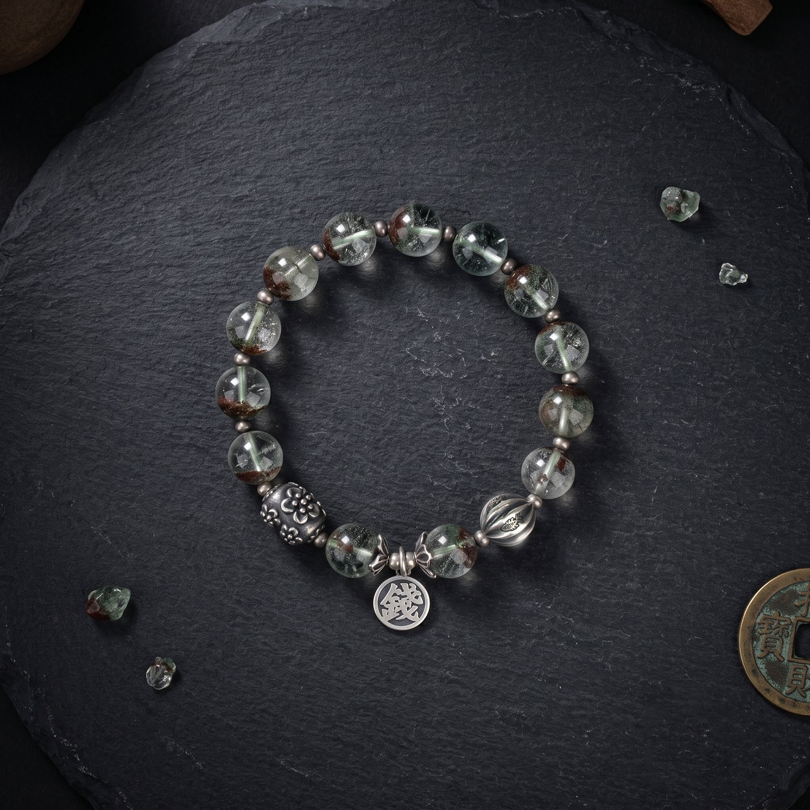 Silver bracelet with green-gray faceted beads and two engraved medallion charms