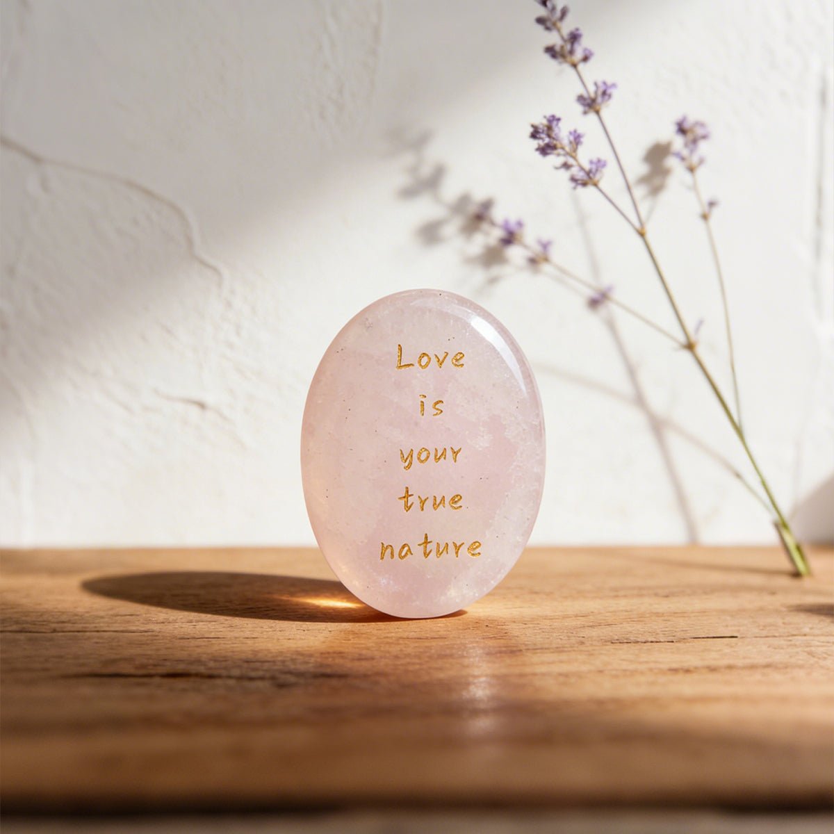 Rose quartz oval stone with gold text reading Love is your true nature