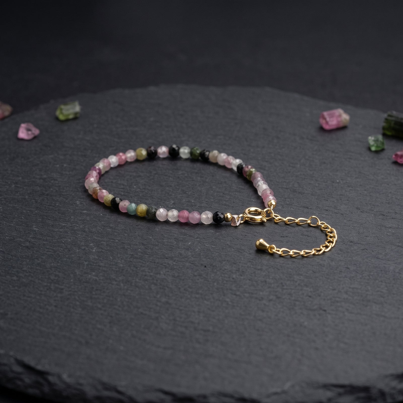 Beaded crystal bracelet with pink, green, and dark stones; gold chain extender