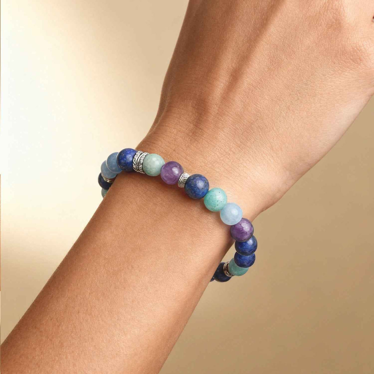 Throat chakra crystal bead bracelet on wrist, round blue and light blue with purple and green beads