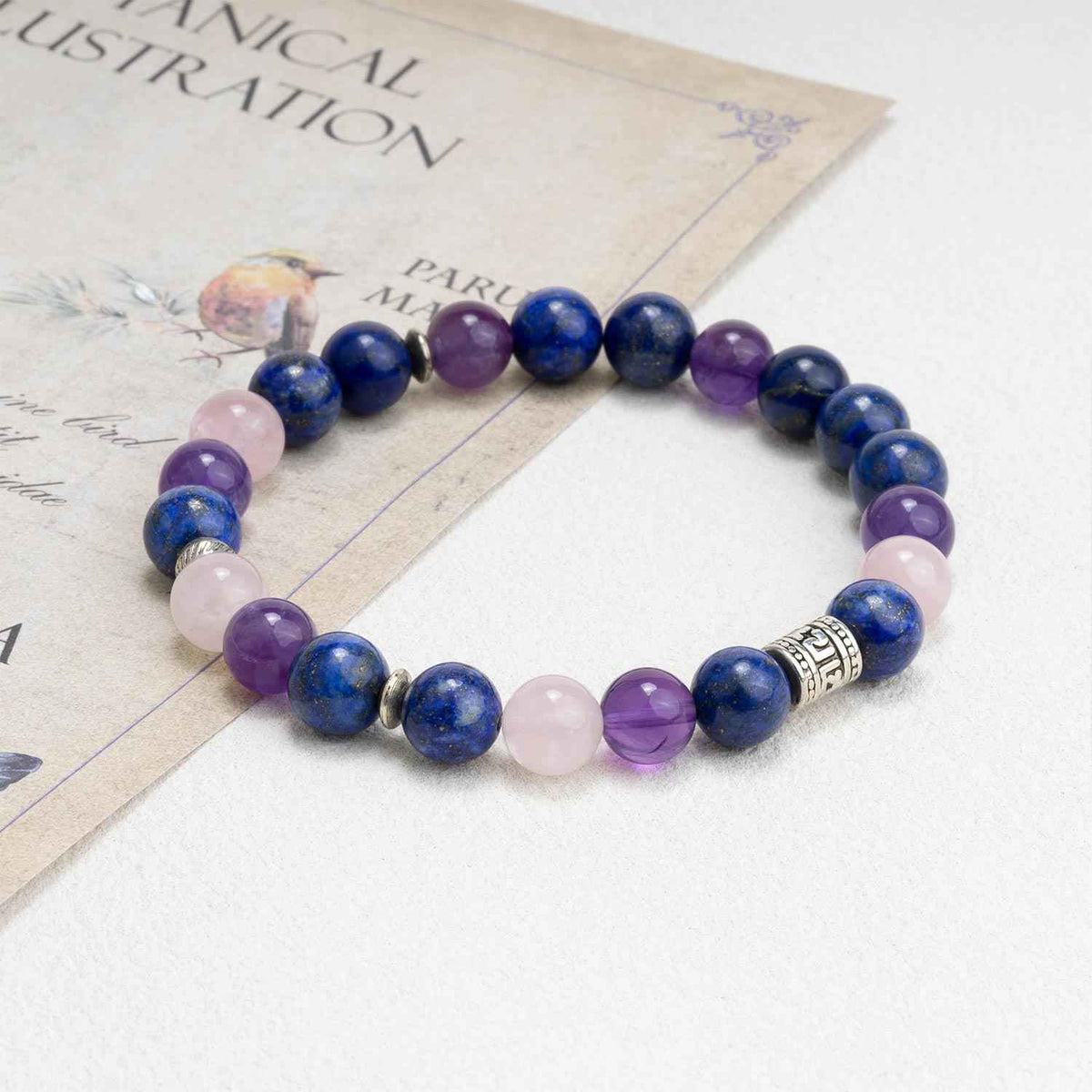 Beaded crystal bracelet with blue, purple, and pale pink stones; metal centerpiece charm