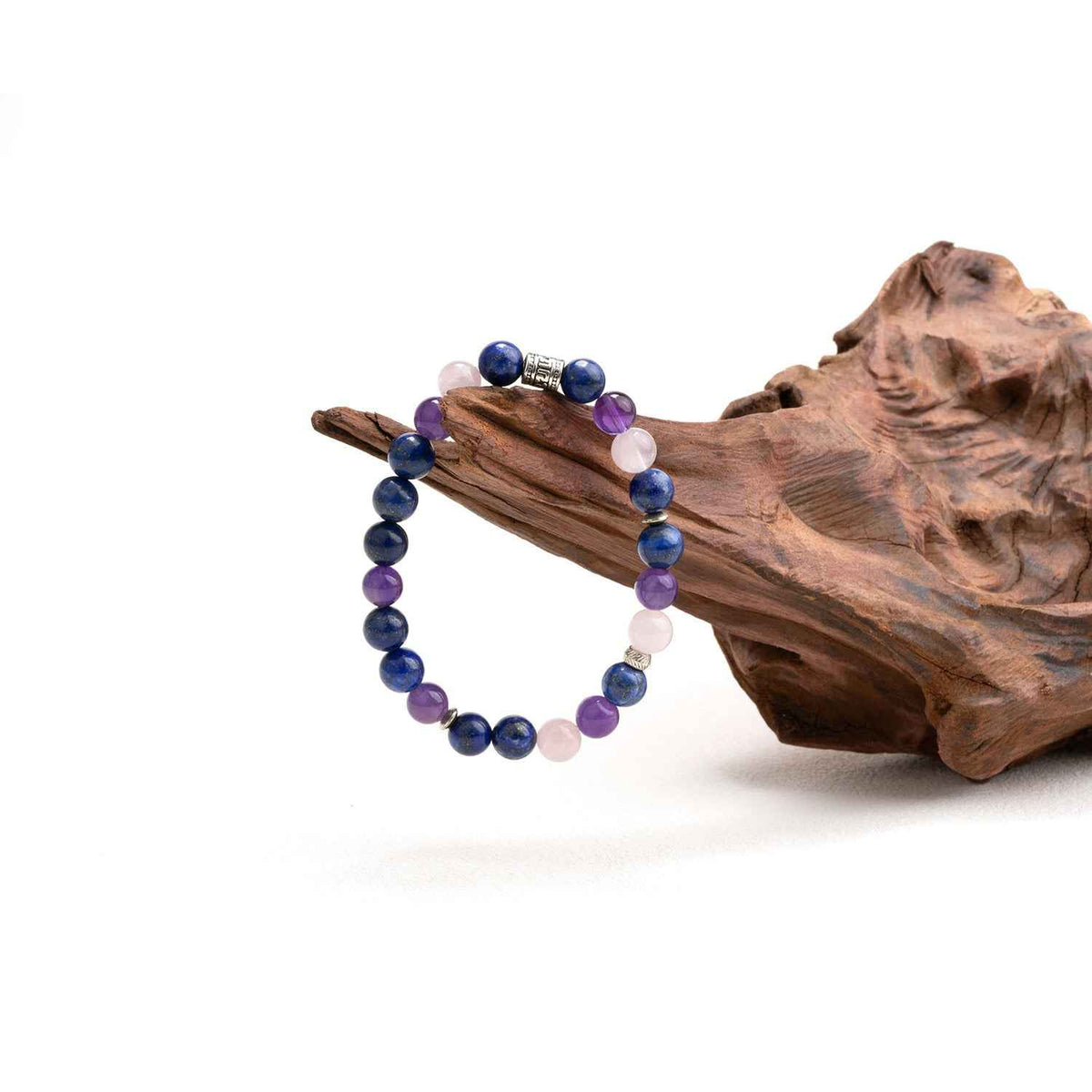 Chakra crystal bracelet on driftwood with blue, purple, and pale pink beads