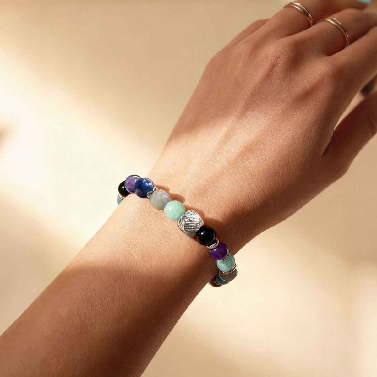 Crystal bead bracelet on wrist, with purple, black, light blue, and aqua stones