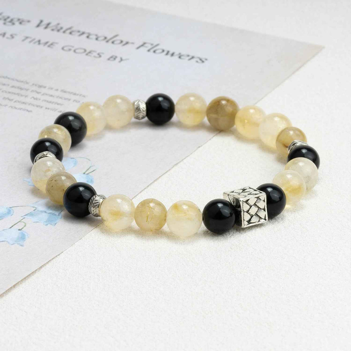 Chakra power crystal bracelet with pale yellow beads, black beads, and silver spacers