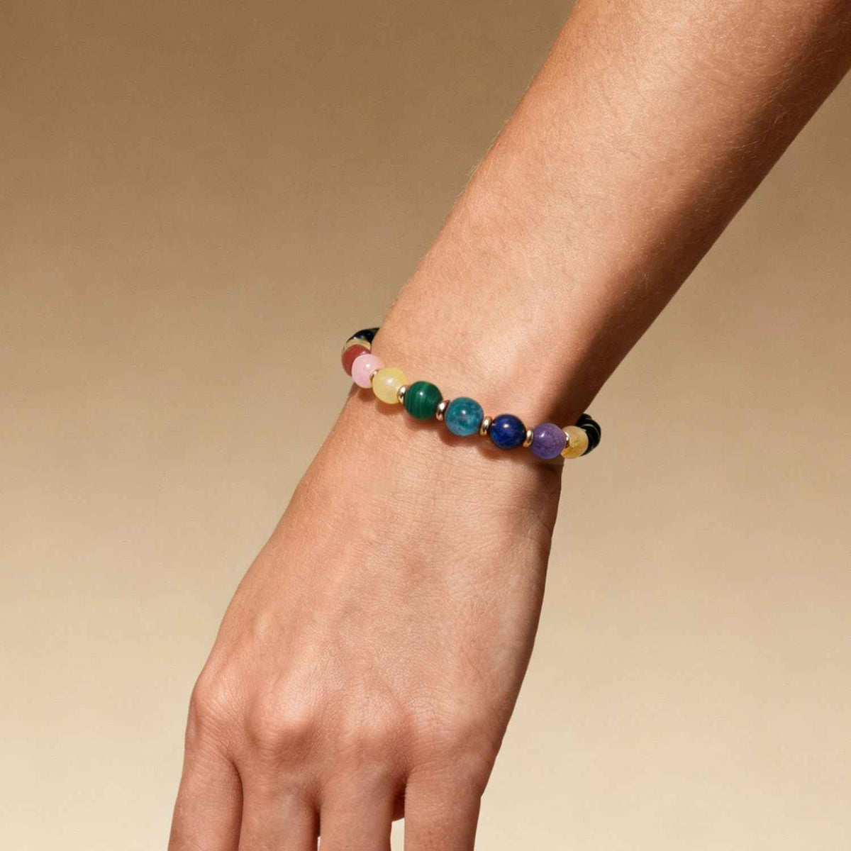 Wrist-worn crystal bead bracelet with black beads and blue, purple, green gemstone accents