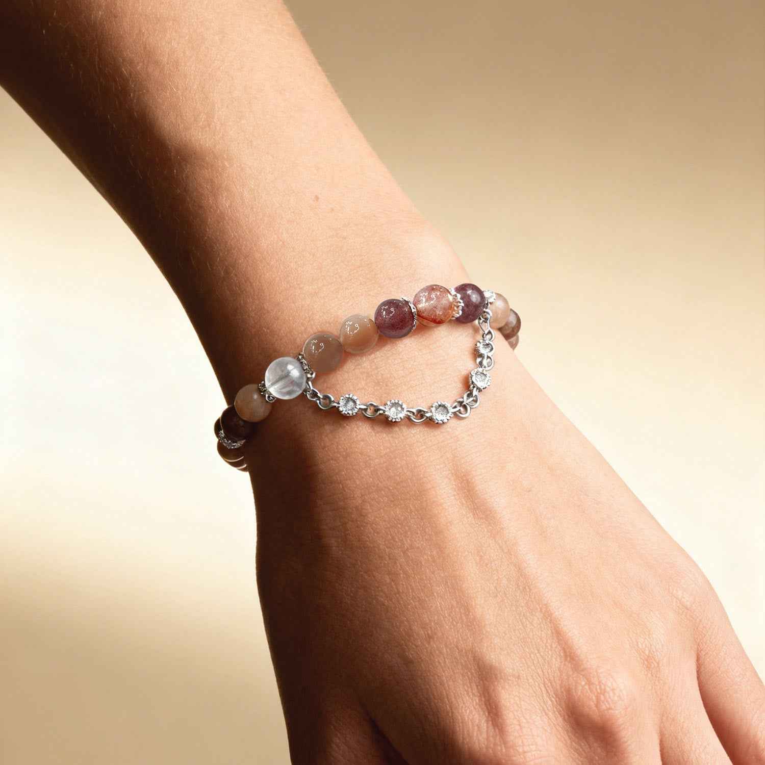 Crystal bracelet on wrist with orange beads, rose beads, and silver chain with links