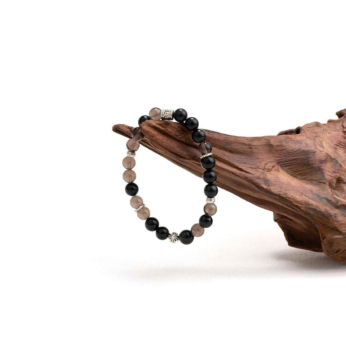 Beaded crystal bracelet with black and smoky brown beads and silver-tone spacer beads on wood.