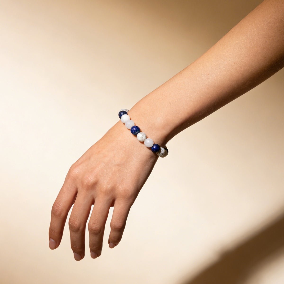 Crystal beaded bracelet on wrist with white and dark blue round beads