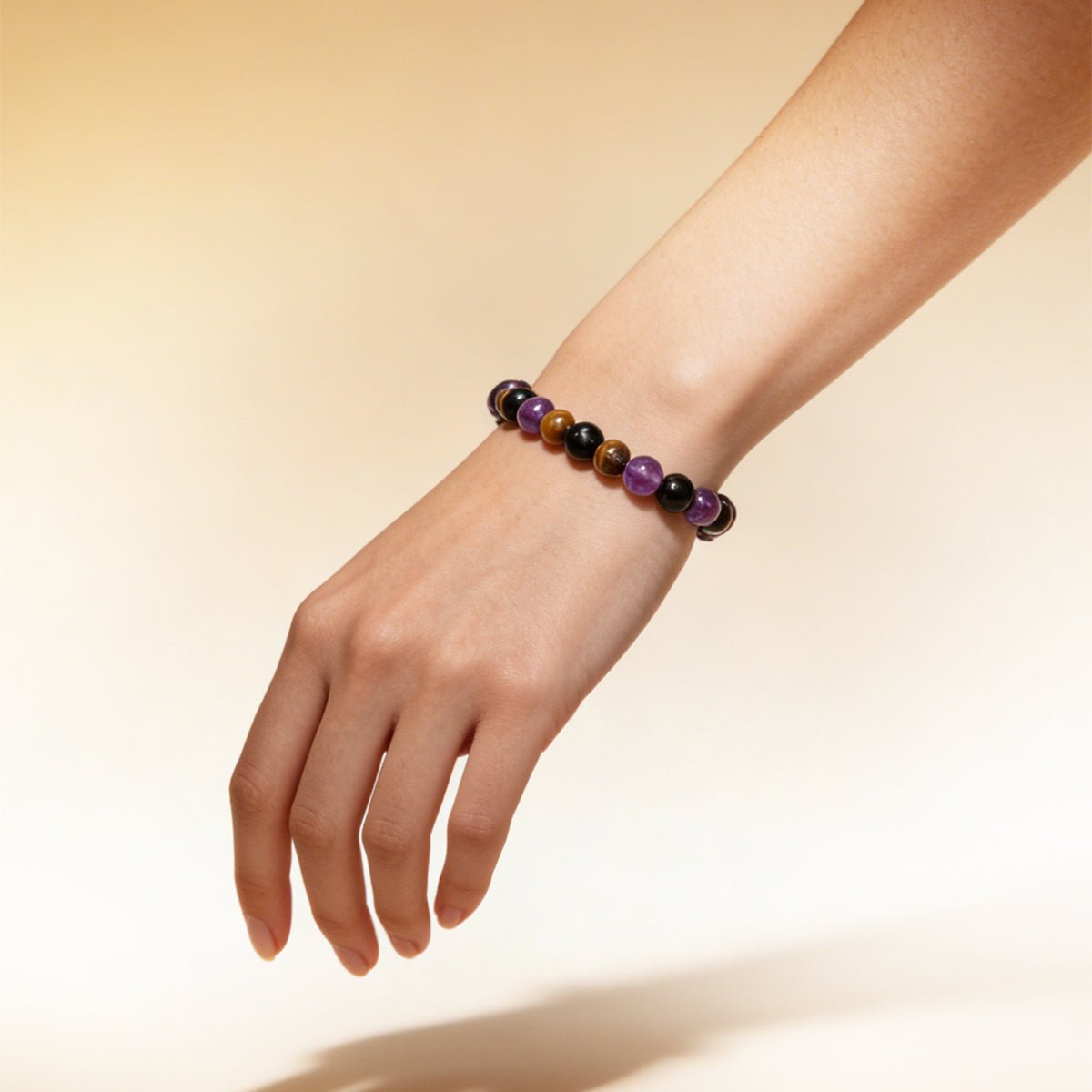 Crystal bead bracelet on wrist with black, purple, and brown round stones