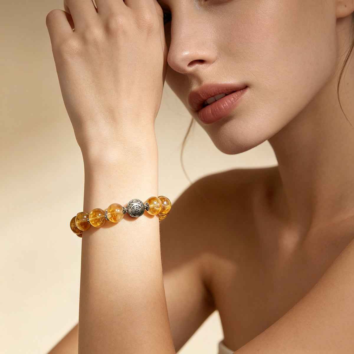 Citrine crystal bracelet on model’s wrist with amber beads and silver-toned accent