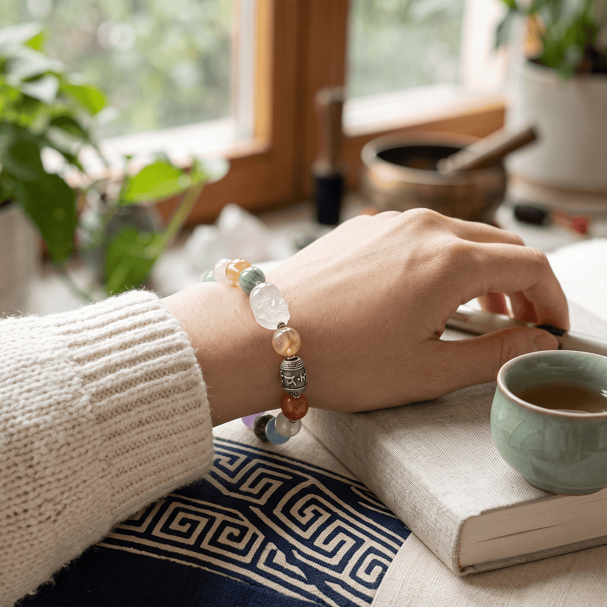 Crystal bracelet on wrist with pastel beads and an engraved metal charm