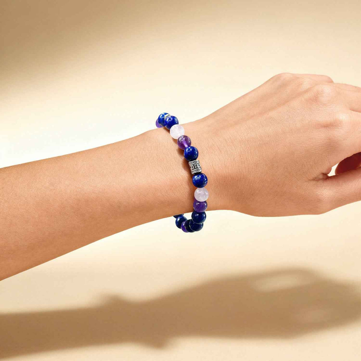 Chakra crystal bracelet on wrist with blue, purple, and pale pink bead strand