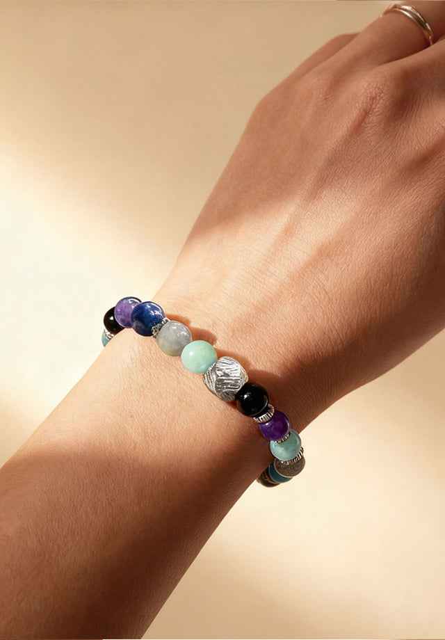 Wrist wearing Amesha Energy crystal bracelet - Natural Amethyst, Lapis Lazuli, and Black Obsidian beads with textured silver charm