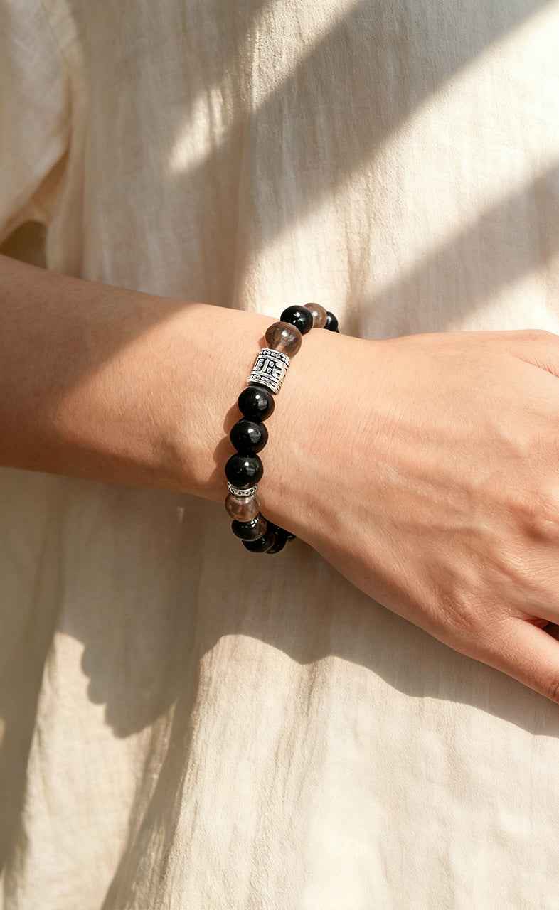 Woman's wrist wearing Amesha Energy Root Chakra Guardian Bracelet - Black Obsidian and brown gemstone beads for daily protection