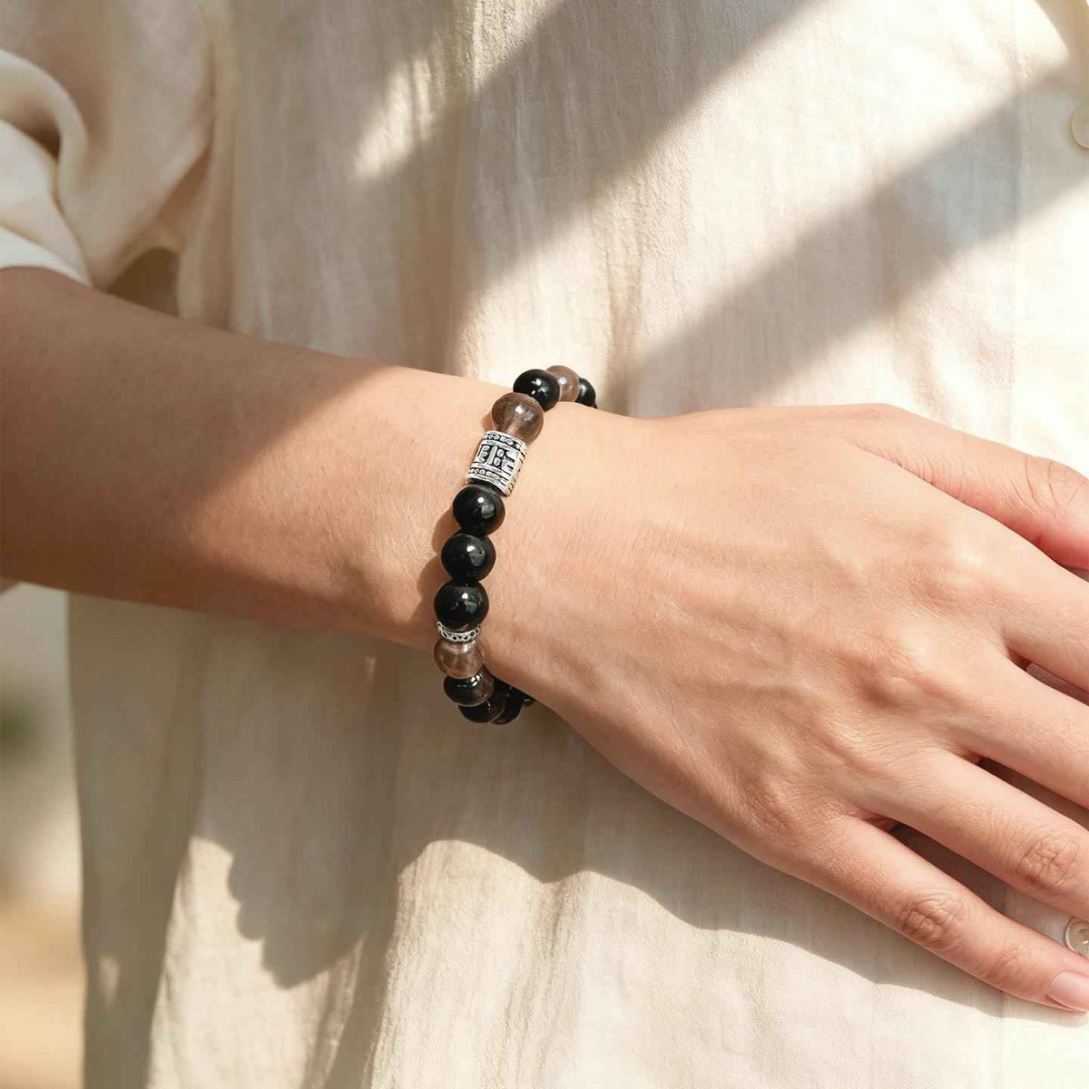 Amesha Energy Root Chakra Guardian Crystal Bracelet - Closeup of woman wearing black Obsidian and brown gemstones for grounding energy