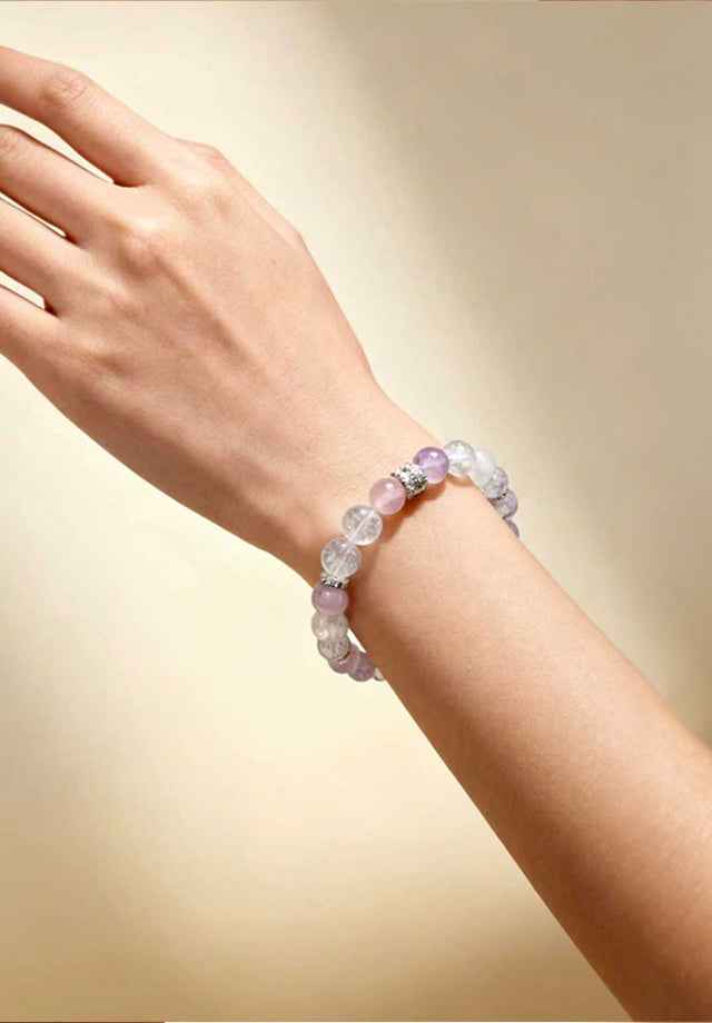 Closeup on wrist wearing Amesha Energy Throat Chakra Truth Crystal Bracelet - Bright blue and light teal gemstone beads with silver charm for clear communication