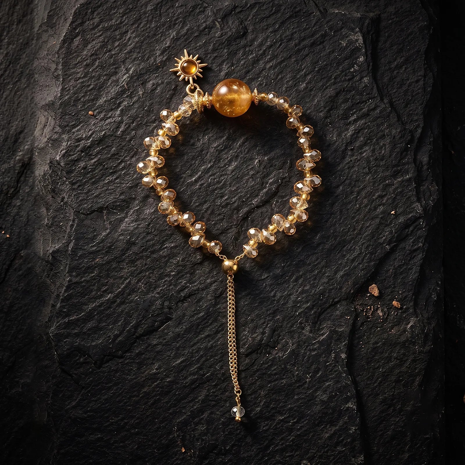 Gold-tone beaded bracelet with round amber stone, small sun pendant, dangling chain